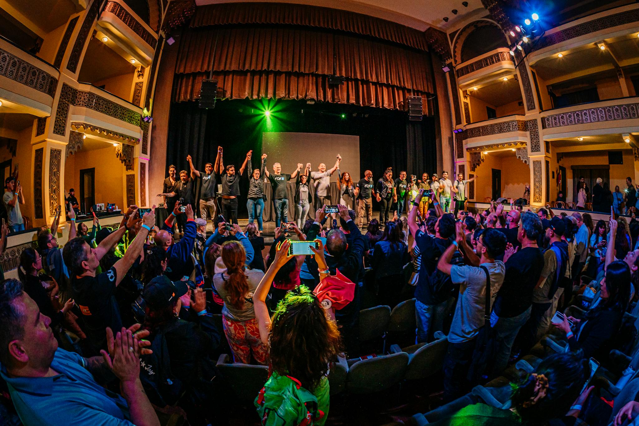 Dynamic theater scene with audience applauding performers on stage.