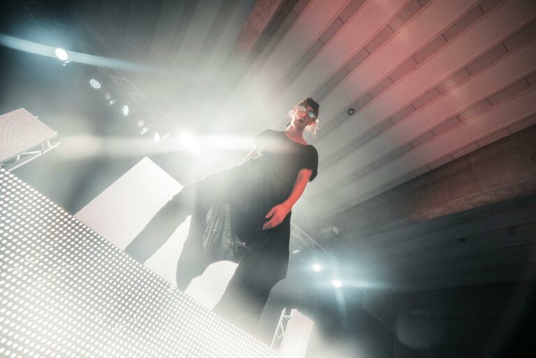 Energetic performer on stage illuminated by colorful spotlights. Captivating low-angle shot