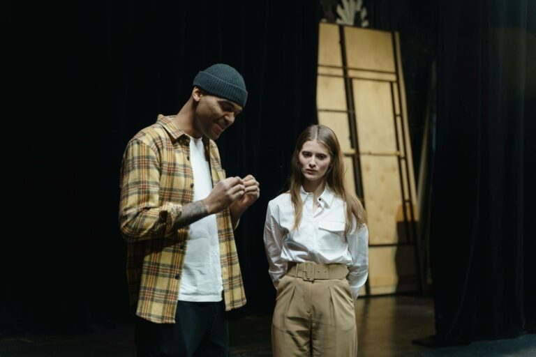 Two actors preparing for a scene during a theater rehearsal indoors.